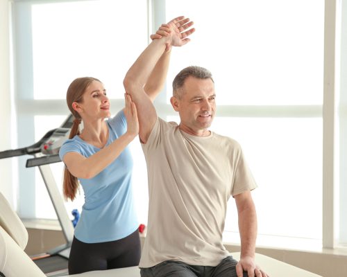 Physiotherapist working with mature patient in rehabilitation ce Physiotherapist working with mature patient in rehabilitation center