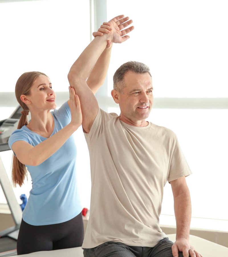 Physiotherapist working with mature patient in rehabilitation ce Physiotherapist working with mature patient in rehabilitation center